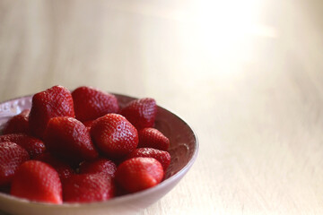 Pink bowl full of fresh strawberries on wooden table. Selective focus.