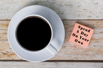 Motivational quote on notepad with white coffee cup on wooden desk.