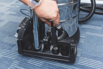 Storing vacuum cleaner attachments on a tray at the back of a chrome upright vacuum device.