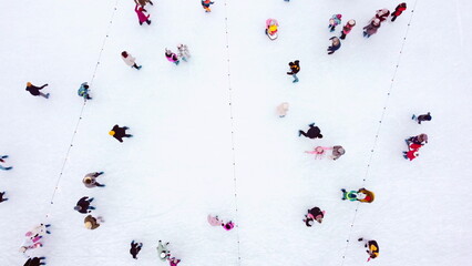 Top view of people skating on large open air ice rink on winter day. Aerial Drone View Flight Over...