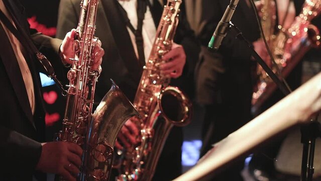 Concert view of saxophonist, a saxophone sax player with vocalist and musical during jazz orchestra performing music on stage 