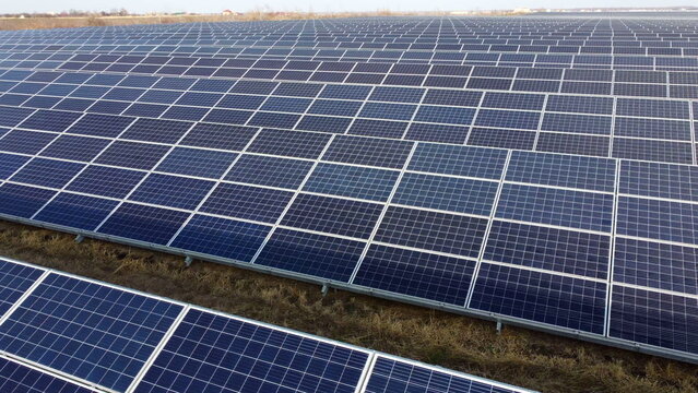 Aerial drone view flight over solar panels on sunny day close-up. Photovoltaic solar panel. Moving over solar panels with sun glare. Production of renewable alternative energy. Green ecological energy