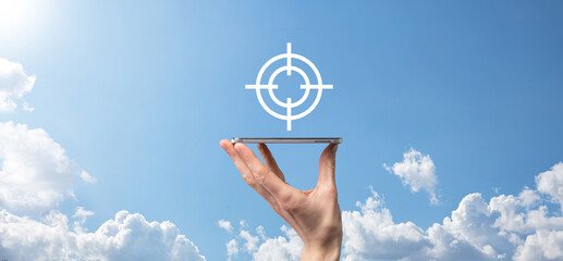 Targeting concept with businessman hand holding target icon dartboard sketch on chalkboard. Objective target and investment goal concept.