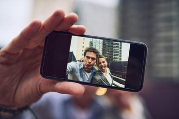 Making some memories. Portrait of two cheerful young work colleagues taking a self portrait together outside during the day.