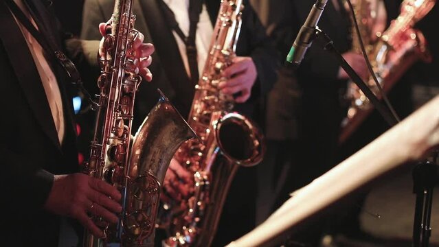 Concert view of saxophonist, a saxophone sax player with vocalist and musical during jazz orchestra performing music on stage 