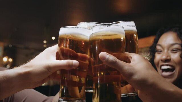 Multi-ethnic group of friends clinking glasses of beer at a restaurant.