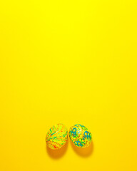Fototapeta na wymiar Yellow and green easter eggs at the bottom on yellow background. Flat lay top view with copy space holidays concept