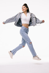 Young woman in jeans clothes running against white background