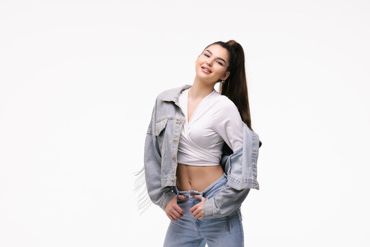 Portrait of a young woman dressed in jeans jacket standing isolated on a white background.