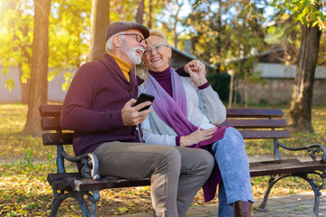 An senior couple listening to music on a bench