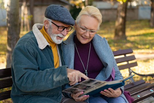 Happy moments, adult parents admiring photos in family album remembering youth