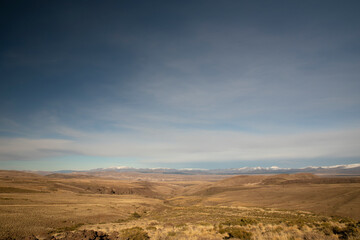 View of the golden valley and meadow under a deep blue sky. The Andes mountain range in the background.