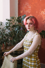 Young fashion stylish woman standing vintage studio, bright make up and colored hair, looking at camera