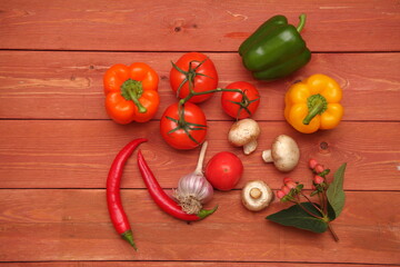 Red pepper. vegetable concept on wooden background. Two red hot peppers. Bulgarian green pepper. branch with tomatoes. garlic, champignons, mushrooms, onions.