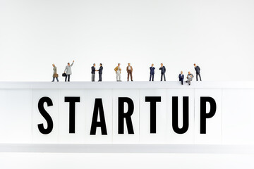 Startup concept. Miniature people on top of the lightbox with a word startup