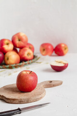 Red apple on a wooden board on a white table. Many fresh apples on a table for making smoothy. Healthy food concept.