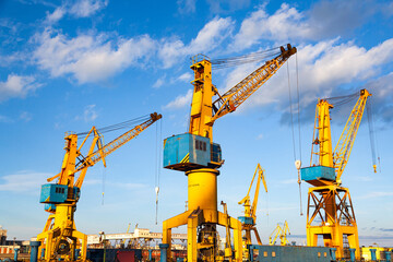 Port cranes on the territory of the seaport in Constanta Romania with blue sky and white clouds. Territory of the seaport with cranes.