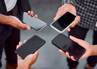 Connected together. Shot of a group of unrecognizable businesspeople using their phones in an office.