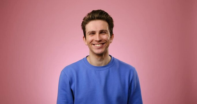 Portrait of handsome young man smiling over pink background