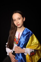 beautiful girl with the flag of Ukraine on a black background. war in Ukraine. patriot of his state. yellow and blue flag. embroidered shirt, traditional Ukrainian clothes.