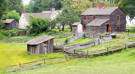 Colonial farmhouse and outbuildings with lush greenery in New England
