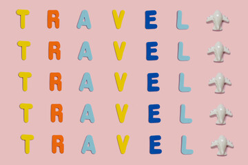 Word Travel spelled with vivid colorful foam letters on a pink background with copy space and a small toy plane. Creative vacation and visit the world cocept. Greeting summer card.