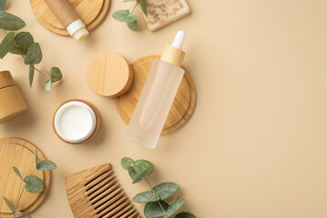 Naklejka na ściany i meble Natural cosmetics concept. Top view photo of transparent bottle with liquid cream jar soap tube hair brush eucalyptus and wooden stands on isolated beige background with copyspace