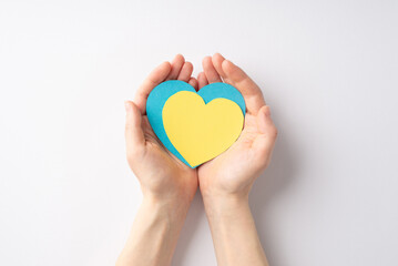 Stop the war in Ukraine concept. First person top view photo of girl's hands holding yellow and blue hearts on palms on isolated white background