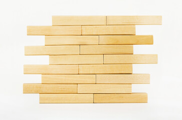 Close-up wall built with toy wooden blocks jenga. wooden brick tower on a white background.