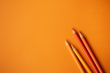 Orange Buntstifte auf orangem Hintergrund. Freiraum für Text