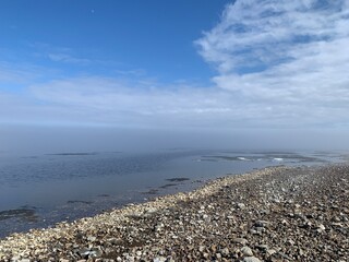 Fototapeta na wymiar pebbly bank of the Volga river in April in Fog and with blue sky