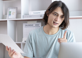 Young Asian men are greeting friends and teachers through video chats and greeting them with cheerful expressions, Online communication , Stay home, New normal, Social distancing, Internet learning.