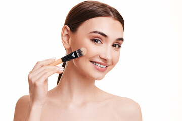 Fototapeta premium woman applying foundation on skin with makeup brush