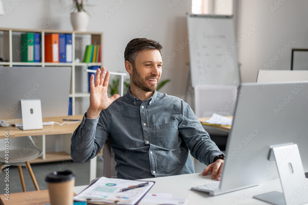 Poster Cheerful mature businessman making video call via computer , working at office and having web conference