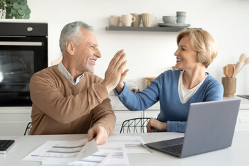 Happy married couple high five each other after paying bills