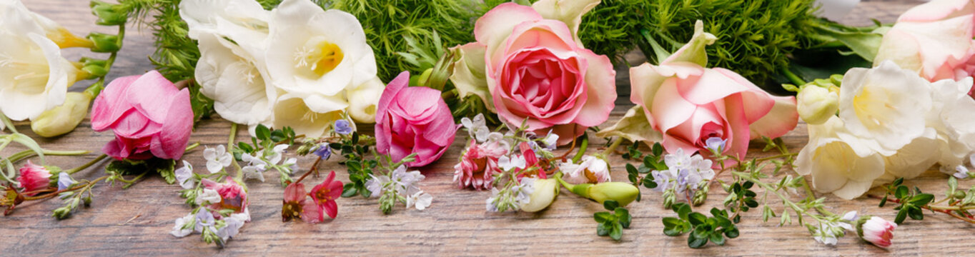 Spring or summer composition made of beautiful flowers, herbs and berries on wooden backdrop. Floristic decoration.
