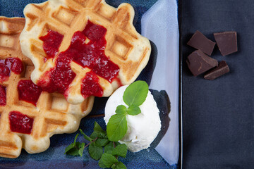 Homemade freshly baked belgian waffles with mint leaves on dark background.
