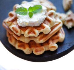 Homemade freshly baked belgian waffles with mint leaves on dark background.