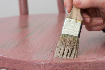 Mano con brocha, aplicando barniz de cera a la silla de madera