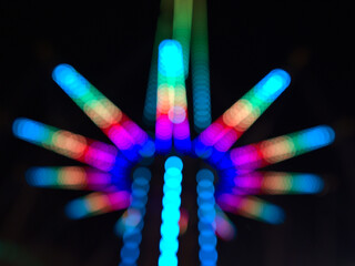 Defocused (blurred) view of the lower part of a drop tower with colorful structure in the dark at Wurstelprater near Wiener Prater in Vienna, Austria.