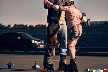 The coach teaches a child to roller skate on the city streets next to the road. Outdoor private...