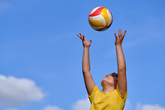 The girl plays volleyball. The child throws the ball with his hands. outdoor play.