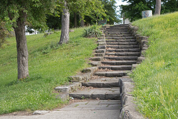 Old gray stone stairway in city park.