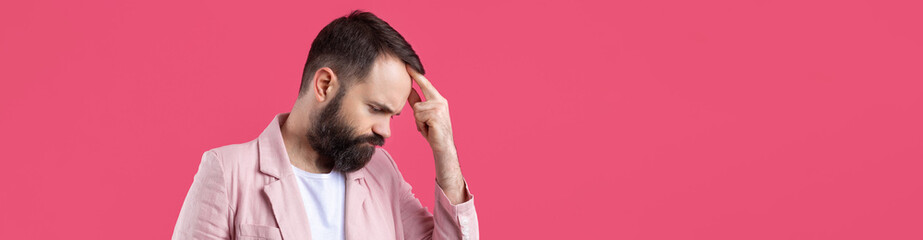 Handsome man with a beard in a pink jacket is thinking over an isolated red background.