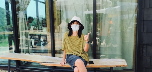 An Asian woman is sitting at a coffee shop in a sunny day.
