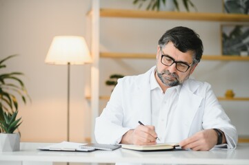 Portrait of attractive mature doctor working in office.
