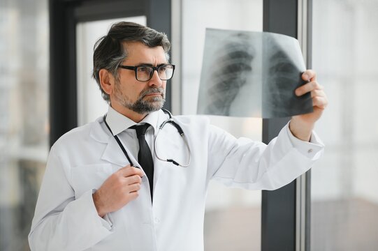older man doctor examines x-ray image of lungs in a clinic
