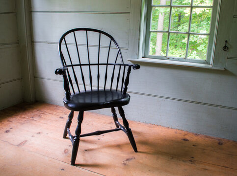 an empty vintage black captain's chair in a rustic colonial house