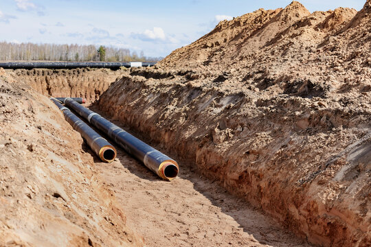 Insulated pipe. Large metal pipes with a plastic sheath laid in a trench. Modern pipeline for supplying hot water and heating to a residential area.