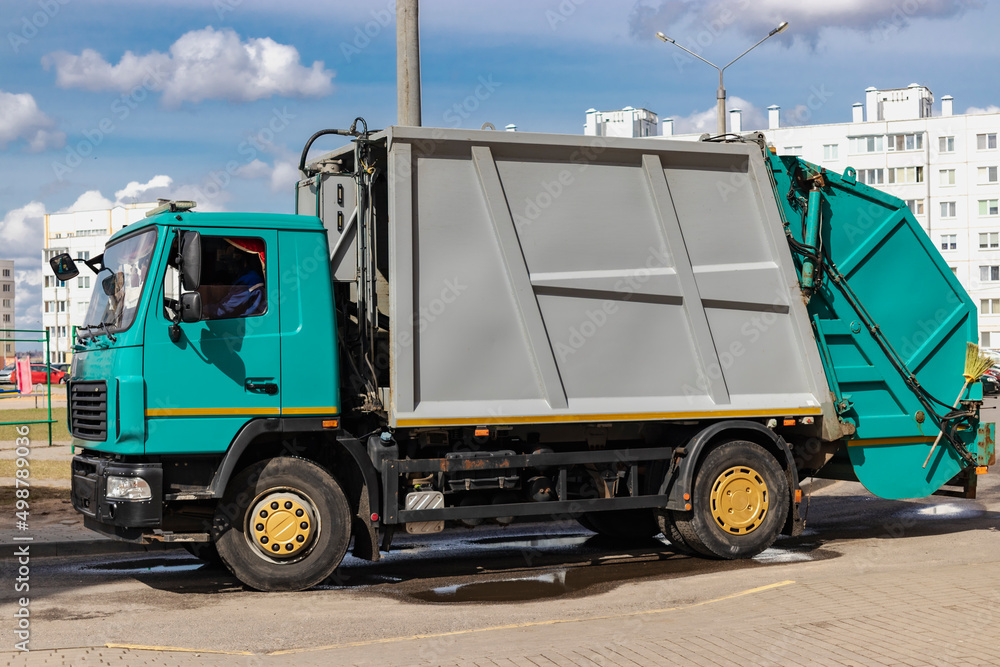 Poster an automobile garbage truck collects garbage in residential areas of a modern city. close-up of a ca